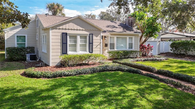 view of front of property with central AC unit, a garage, and a front lawn