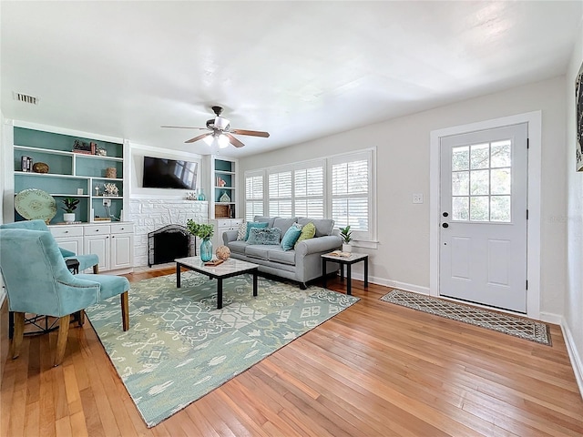 living room with built in shelves, plenty of natural light, light hardwood / wood-style floors, and ceiling fan