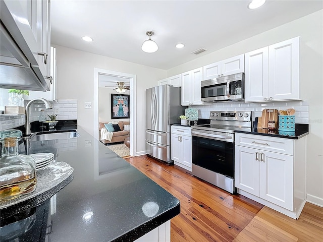 kitchen featuring sink, tasteful backsplash, light wood-type flooring, appliances with stainless steel finishes, and white cabinets