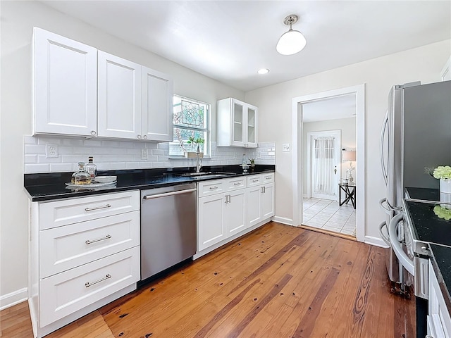 kitchen with sink, white cabinetry, tasteful backsplash, light hardwood / wood-style flooring, and stainless steel appliances