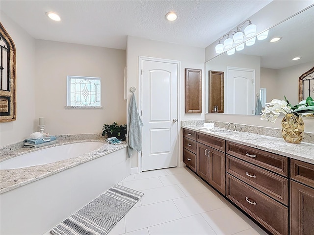 bathroom featuring tile patterned floors, vanity, a bath, and a textured ceiling