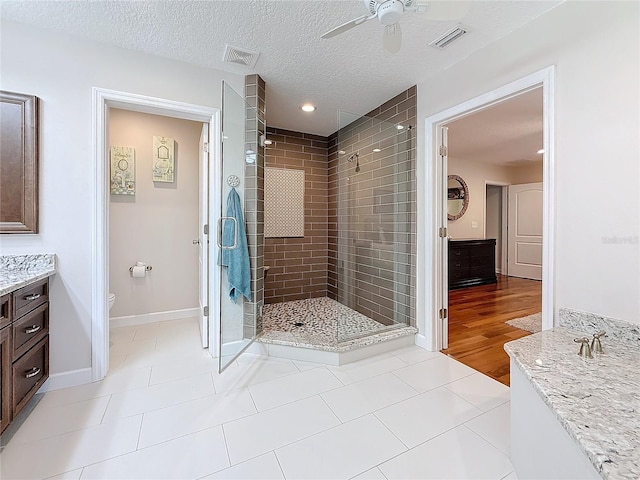 bathroom featuring vanity, toilet, a textured ceiling, and a shower with shower door