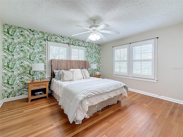 bedroom featuring ceiling fan, hardwood / wood-style floors, and a textured ceiling