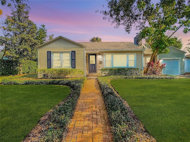 single story home featuring a garage and a lawn