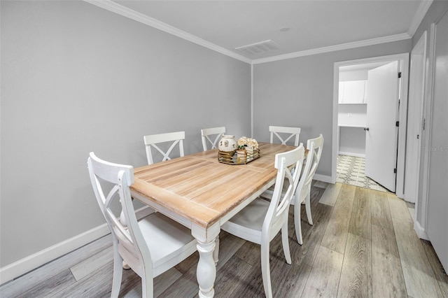 dining area featuring crown molding and light hardwood / wood-style floors