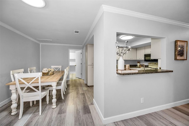 kitchen featuring white electric stove, white cabinets, kitchen peninsula, crown molding, and light hardwood / wood-style flooring