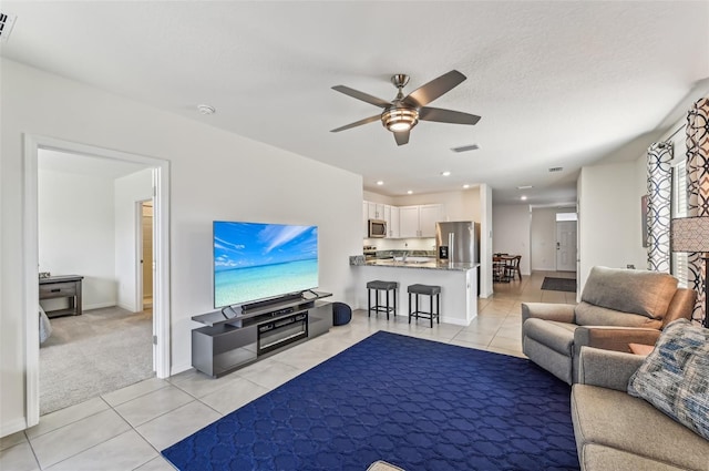 tiled living room with a textured ceiling and ceiling fan