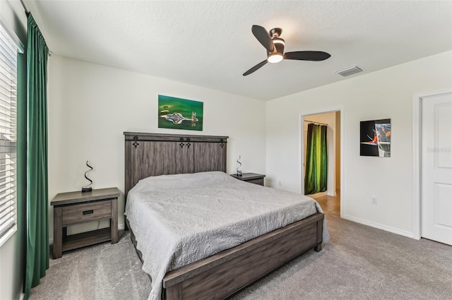 bedroom with ceiling fan, light carpet, and a textured ceiling