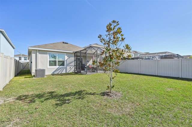 rear view of house with central AC, a lanai, and a lawn