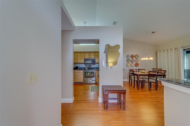 kitchen with black microwave, stainless steel range oven, light wood finished floors, and dark countertops