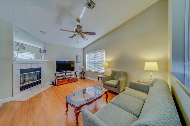 living room featuring visible vents, lofted ceiling, ceiling fan, wood finished floors, and a fireplace