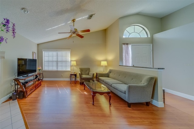 living area with lofted ceiling, plenty of natural light, visible vents, and wood finished floors