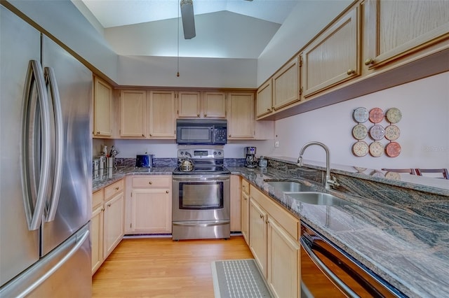 kitchen featuring ceiling fan, a sink, light wood-style floors, black appliances, and dark stone countertops