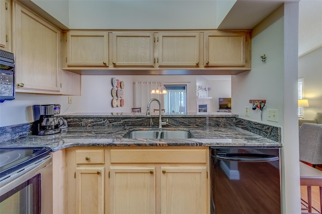 kitchen with dishwasher, dark stone counters, a sink, and light brown cabinetry