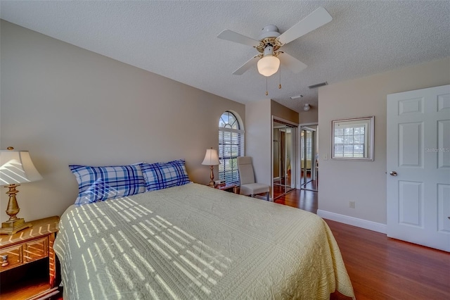 bedroom featuring visible vents, ceiling fan, a textured ceiling, wood finished floors, and baseboards