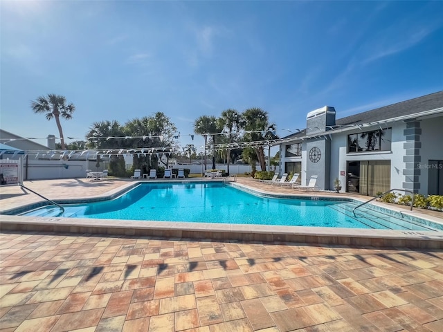 community pool with fence and a patio