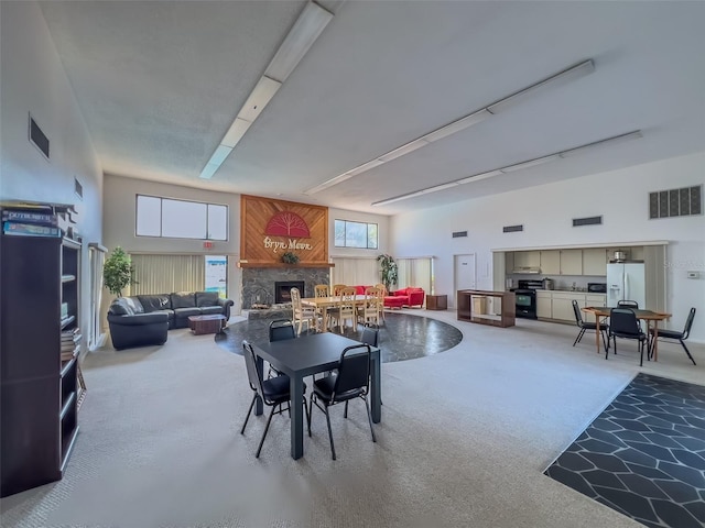 dining space featuring a high ceiling, a fireplace, and visible vents