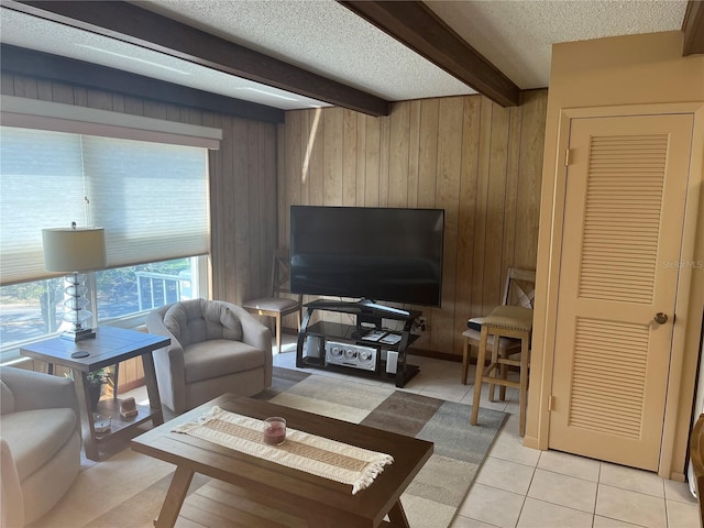 living room featuring light tile patterned floors, beamed ceiling, a textured ceiling, and wood walls