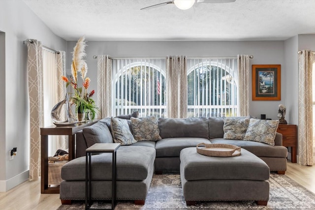 living room featuring ceiling fan, a textured ceiling, and light wood-type flooring