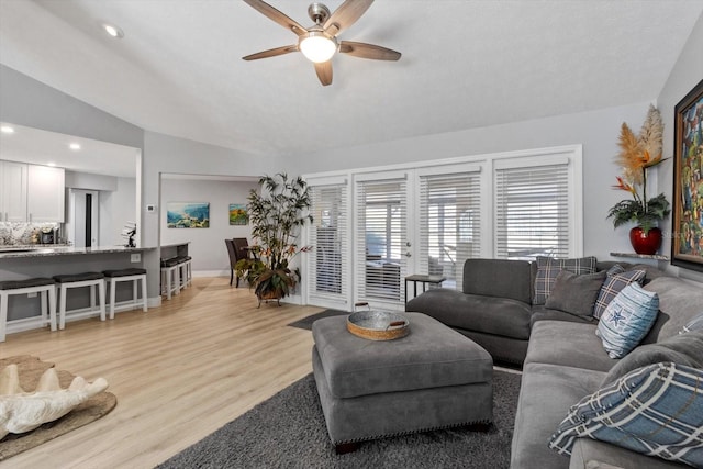 living room featuring ceiling fan, light hardwood / wood-style floors, and vaulted ceiling