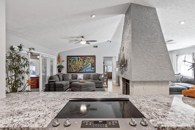 kitchen featuring a healthy amount of sunlight, vaulted ceiling, light stone countertops, and a textured ceiling