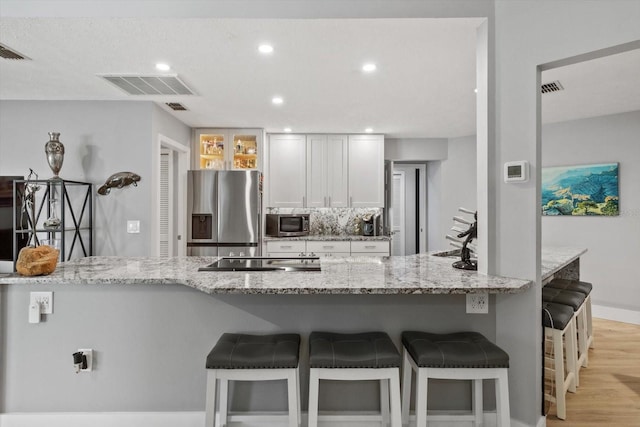 kitchen with white cabinetry, light stone countertops, stainless steel appliances, and sink