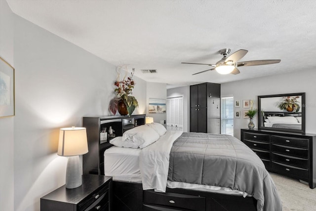 carpeted bedroom featuring ceiling fan, a closet, and a textured ceiling