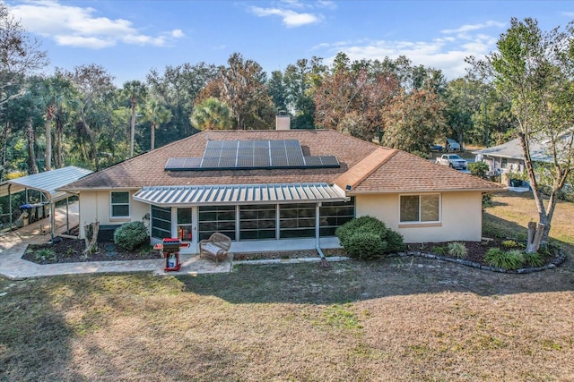 view of front facade featuring a front yard, a sunroom, and solar panels