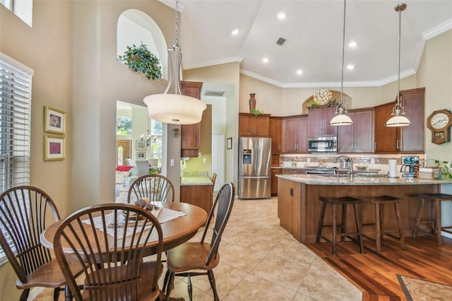 kitchen featuring stainless steel appliances, crown molding, hanging light fixtures, and dark stone counters