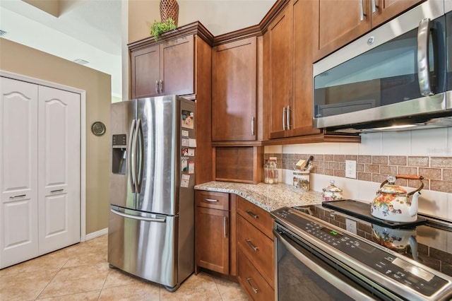 kitchen with stainless steel appliances, light stone countertops, decorative backsplash, and light tile patterned floors