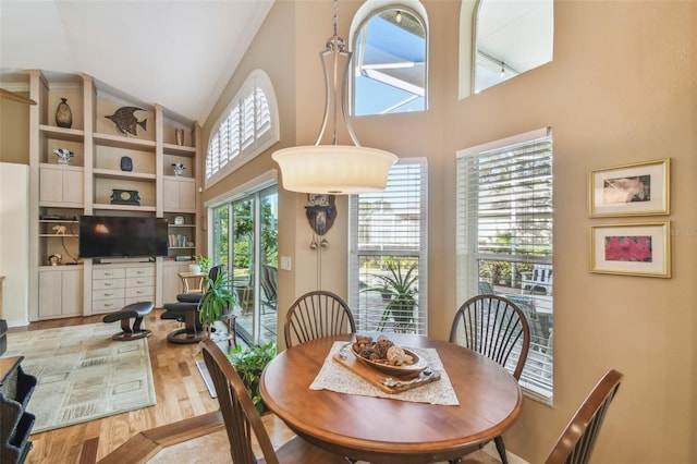 dining room featuring high vaulted ceiling and light wood-type flooring