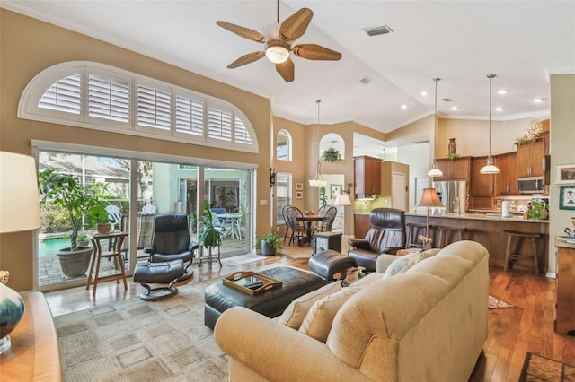 living room featuring hardwood / wood-style flooring, ceiling fan, crown molding, and high vaulted ceiling