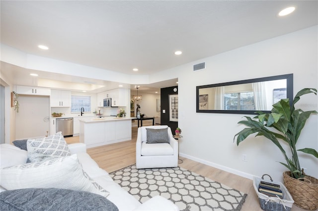 living room featuring sink, a wealth of natural light, and light hardwood / wood-style floors