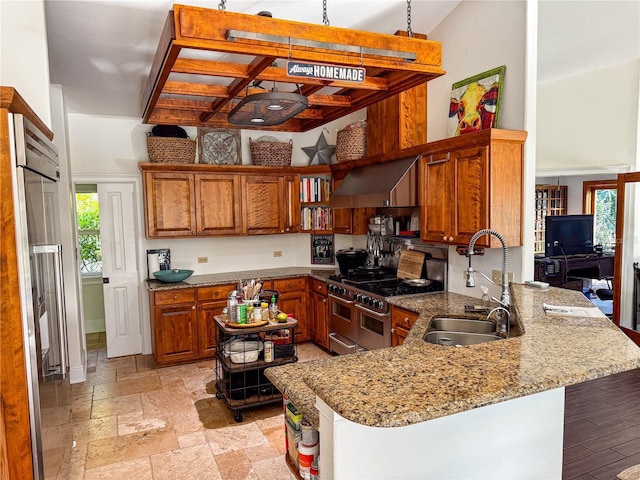 kitchen with sink, high quality appliances, a high ceiling, light stone countertops, and kitchen peninsula