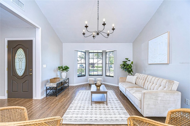 living room with dark hardwood / wood-style flooring, vaulted ceiling, and an inviting chandelier