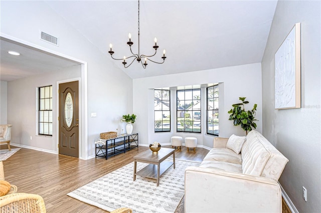 living room with lofted ceiling, a notable chandelier, and hardwood / wood-style flooring