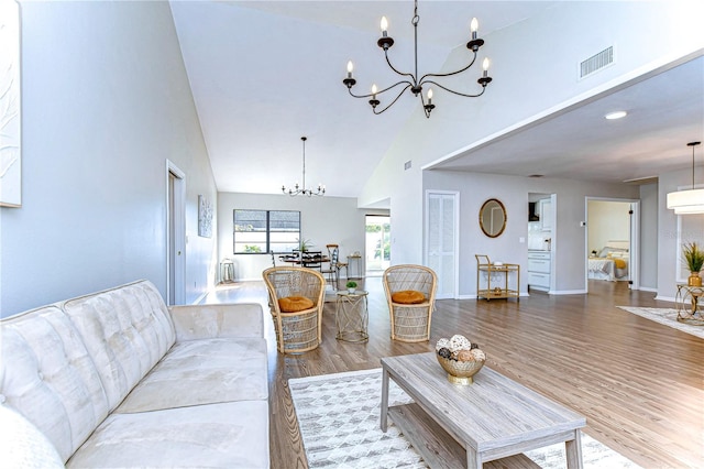 living room featuring hardwood / wood-style flooring, high vaulted ceiling, and a chandelier