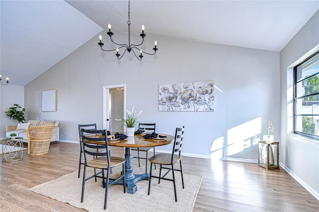 dining area with hardwood / wood-style flooring, high vaulted ceiling, and a notable chandelier