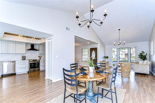 dining room with an inviting chandelier, wood-type flooring, and high vaulted ceiling