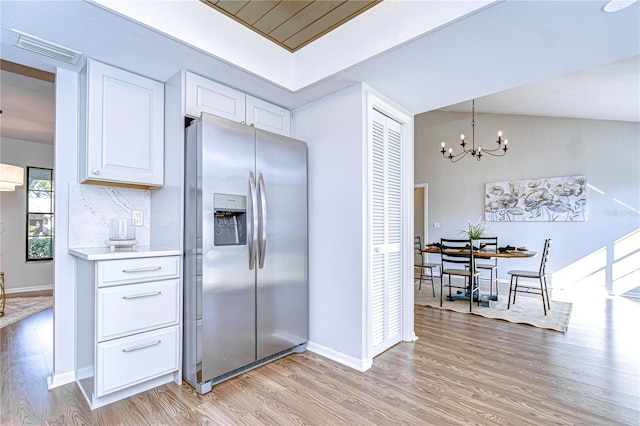 kitchen with stainless steel fridge with ice dispenser, decorative light fixtures, light hardwood / wood-style flooring, and white cabinets