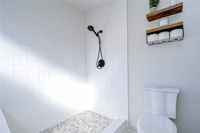 bathroom featuring tiled shower and toilet