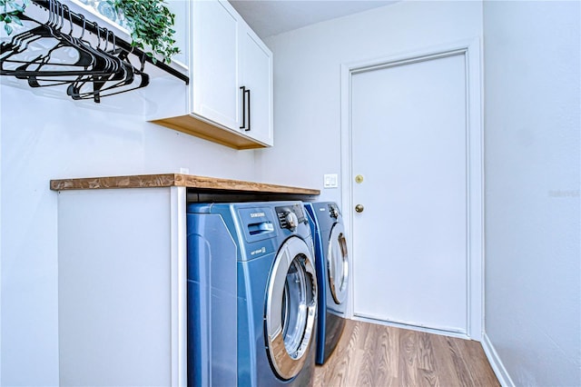 clothes washing area featuring cabinets, washing machine and dryer, and light wood-type flooring