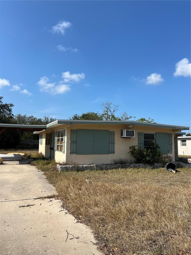 view of front of home featuring an AC wall unit and a carport