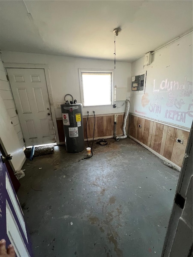 misc room featuring electric panel, water heater, and wood walls