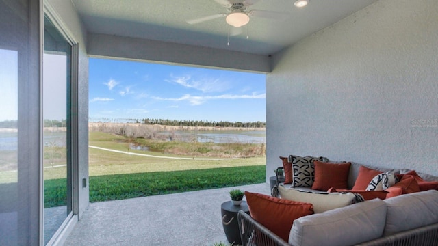 sunroom with plenty of natural light, ceiling fan, and a water view