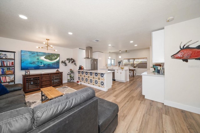 living room featuring an inviting chandelier, a textured ceiling, and light hardwood / wood-style floors