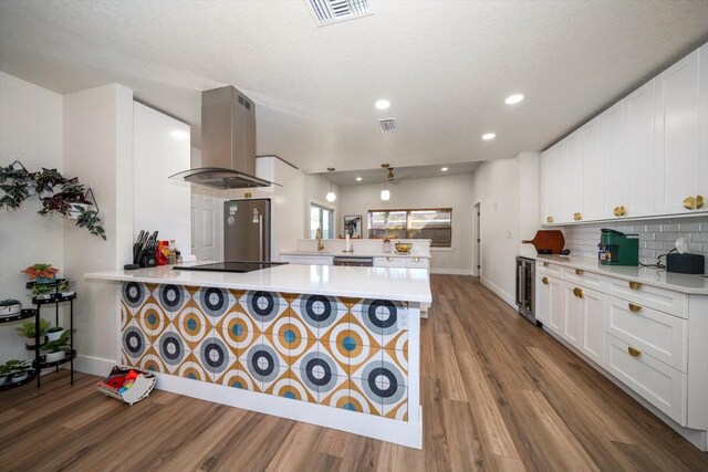 kitchen with island range hood, white cabinetry, wine cooler, kitchen peninsula, and black electric cooktop