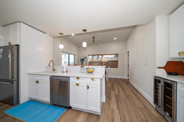 kitchen featuring white cabinetry, hanging light fixtures, appliances with stainless steel finishes, kitchen peninsula, and beverage cooler