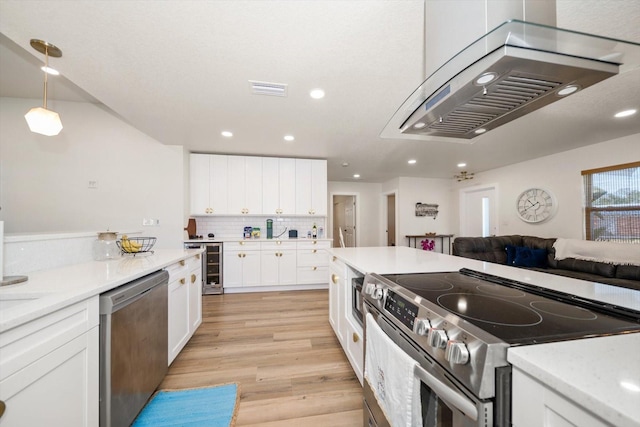 kitchen featuring decorative light fixtures, wine cooler, white cabinets, stainless steel appliances, and light wood-type flooring