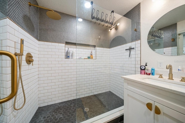 bathroom with tiled shower and vanity